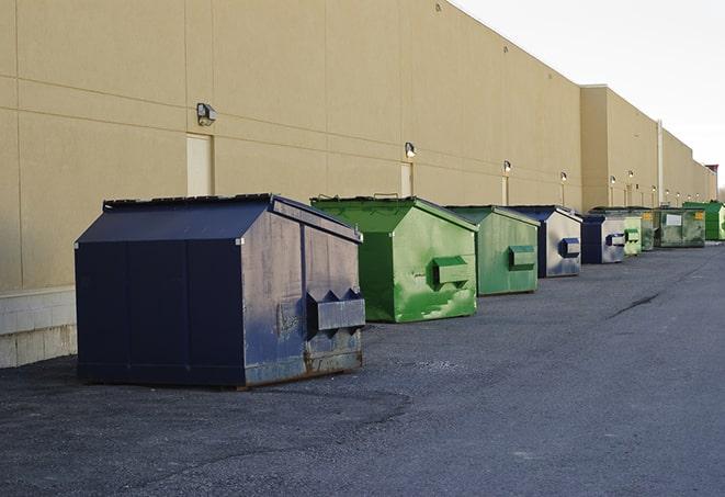 a series of colorful, utilitarian dumpsters deployed in a construction site in Andover